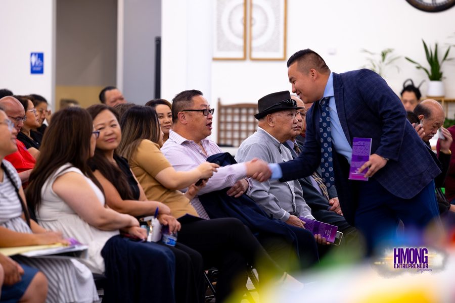 Two people shaking hands and smiling at a community business conference in Fresno.